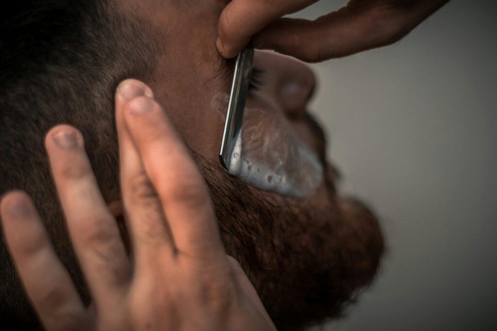 A man having his upper cheek shaved by a barber, representing beards in Islam