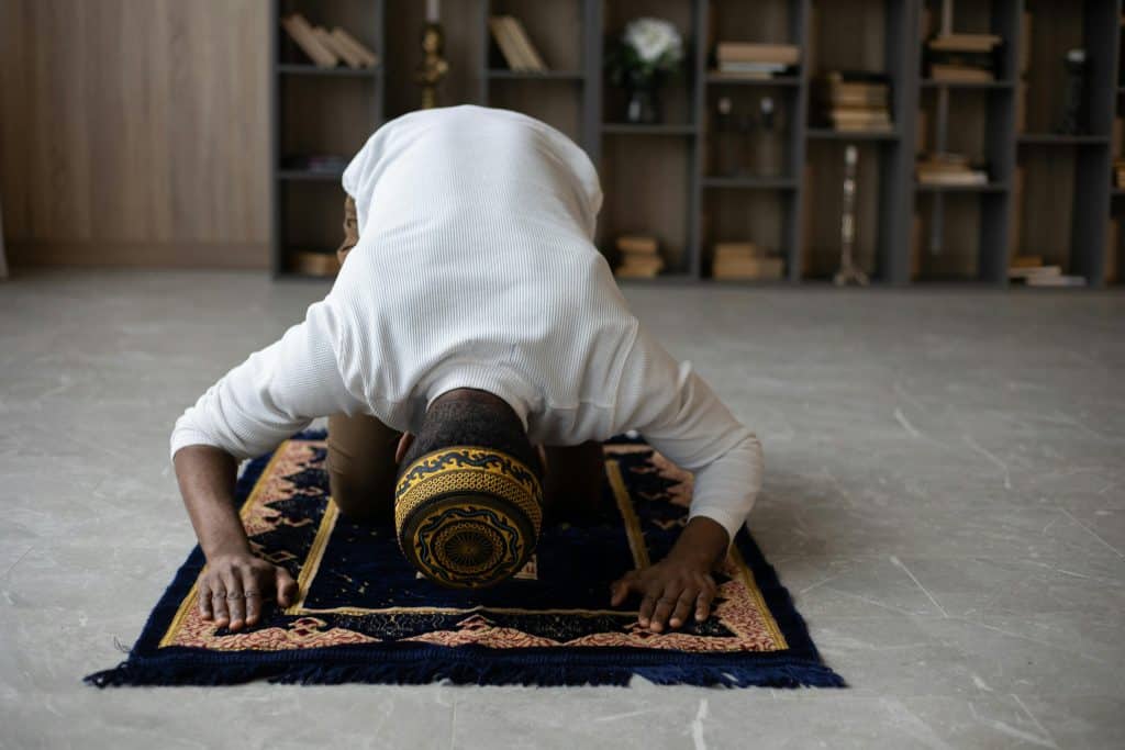 A Muslim man prostrating in prayer at home, representing Making Up Missed Prayers